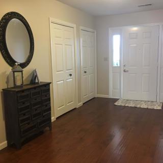 A neat entryway with a mirror above a dresser and a white front door.