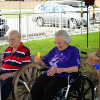 Two elderly individuals enjoying a sunny day at a park.