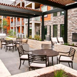 A modern outdoor patio area with tables and chairs, surrounded by contemporary architecture.
