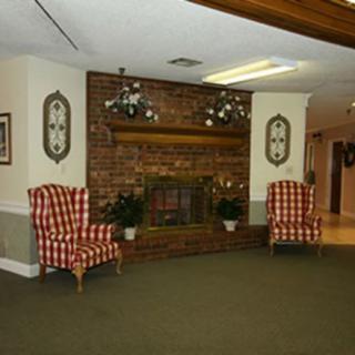 A cozy living room with a brick fireplace and two patterned armchairs.