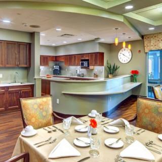 A modern dining area with a neatly set table and an open kitchen in the background.
