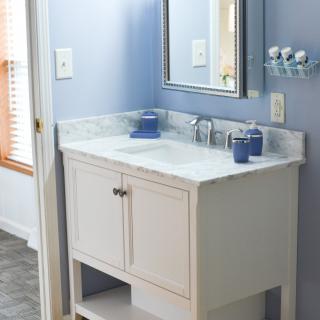 A modern bathroom with a white vanity and marble countertop against blue walls.