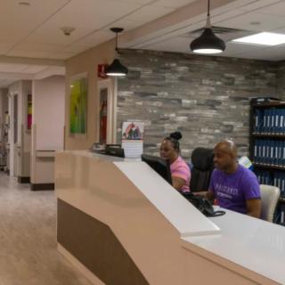Two people working at a reception desk in an office setting.