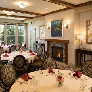 Elegant dining room with round tables set for a meal, featuring a cozy fireplace.