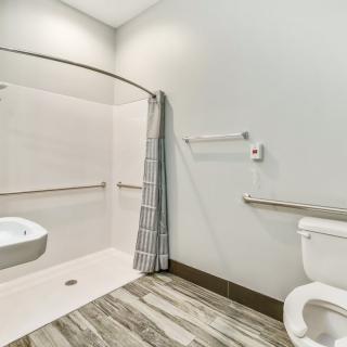 An accessible bathroom with a walk-in shower, toilet, and grab bars.