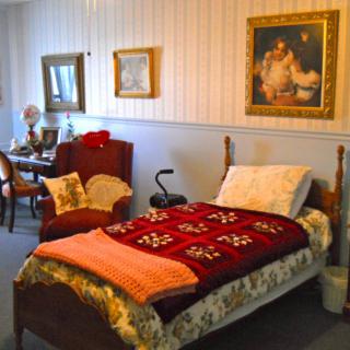 A cozy bedroom with vintage furniture and decorative paintings on the walls.