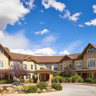 A charming residential building with a beautifully landscaped garden under a clear blue sky.