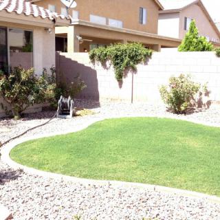 A neatly landscaped yard with a well-maintained lawn bordered by gravel and shrubs.