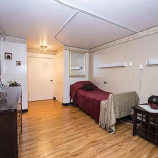 A simple bedroom with a single bed and wooden flooring.