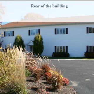 Rear view of a white building with surrounding landscaping.
