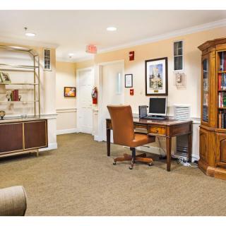 An office space featuring a desk with a computer and chair, surrounded by cabinets and bookshelves.