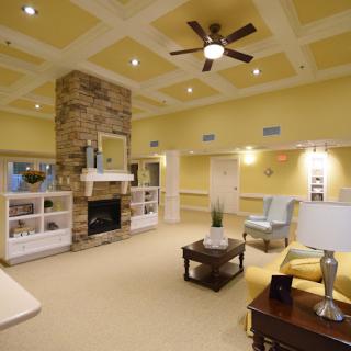 A cozy and modern living room with a stone fireplace, ceiling fan, and comfortable seating.