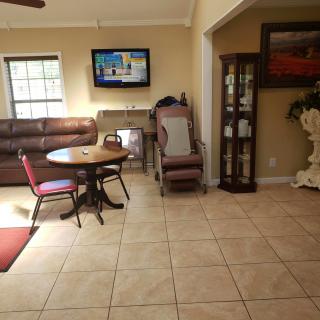 A cozy living room with a television, sofa, and dining table set on a tile floor.