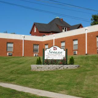 A brick building with a sign in front, set against a clear blue sky and green grass.