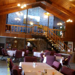A cozy dining area with wooden ceilings, chandeliers, and a mezzanine.