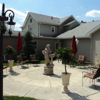 A cozy patio area with outdoor seating, statues, and umbrellas surrounded by a house.