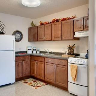 A cozy kitchen with wooden cabinets, a white refrigerator and stove, decorated with autumn-themed accents.
