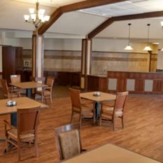 A spacious restaurant interior with wooden floors, tables, and chairs arranged neatly.