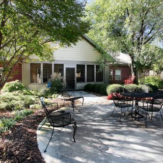 A tranquil patio area with outdoor seating surrounded by lush greenery and trees.
