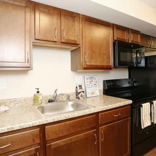 Modern kitchen with wooden cabinets and black appliances.
