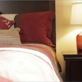 A cozy bedroom setup with warm-toned pillows and a bedside lamp.