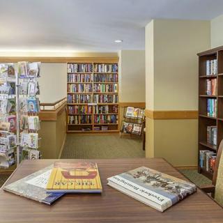 A cozy library corner with bookshelves, a reading table, and magazines neatly arranged.