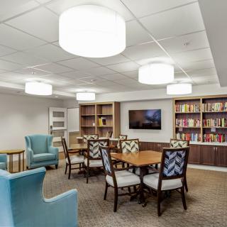 A cozy reading room with bookshelves, tables, and comfortable seating.