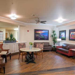 A cozy and well-decorated living room with sofas, a round table, and various artworks on the walls.