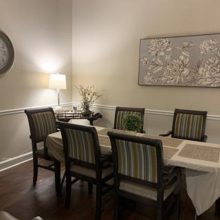 A cozy dining room with a six-seat table and decorative wall art.