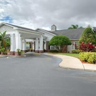 A well-maintained building with a driveway surrounded by lush greenery under a cloudy sky.