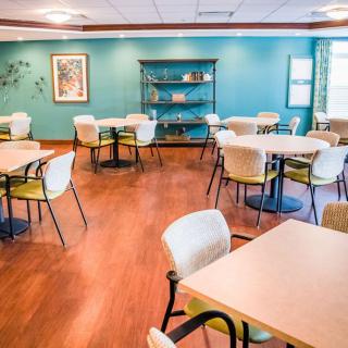 A cozy dining area with neatly arranged tables and chairs, featuring a wooden floor and decorative elements.