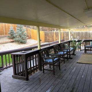 A spacious wooden deck with chairs overlooking a fenced backyard.