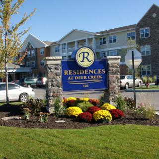 Image of a residential apartment complex with well-maintained landscaping and a sign that reads 'Residences at Field Creek'.
