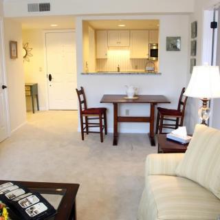 A cozy apartment interior featuring a living room with a small dining area and a view into the kitchen.