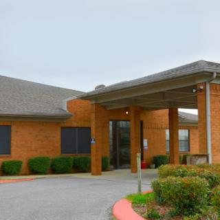 A view of a brick building with an inviting entrance and landscaped surroundings.