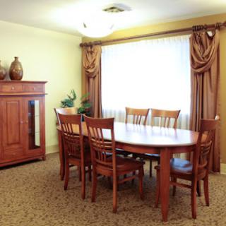 A cozy dining room featuring a wooden table and chairs, adorned with elegant curtains.