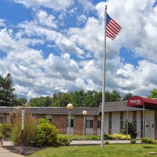 A building showcasing an American flag against a backdrop of fluffy clouds.