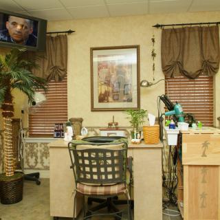 An interior view of a nail salon featuring a work desk, a chair, and decorative elements such as plants and artwork.