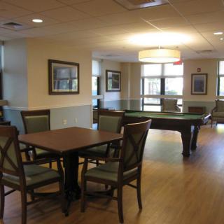 A well-lit recreation room featuring a pool table and seating area.