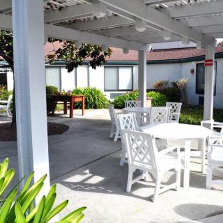 A sunny outdoor patio with white furniture under a pergola.