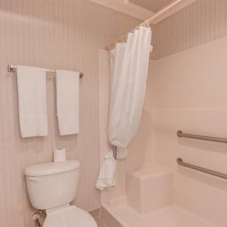 A clean bathroom with towels, a toilet, and a shower area equipped with grab bars.