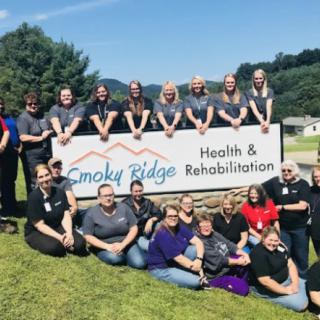 A group of people posing in front of the Smoky Ridge Health & Rehabilitation sign.