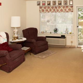 A cozy living room with two brown chairs, a lamp, and a decorated window.