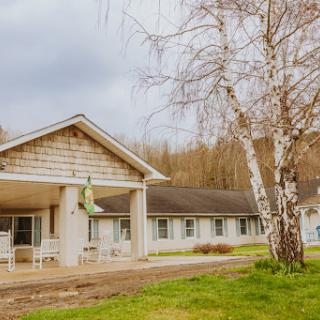 A quaint motel set against a backdrop of nature, featuring a charming birch tree and an overcast sky.