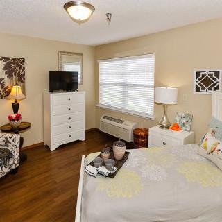 A cozy and well-decorated bedroom featuring a bed, dresser, TV, and various decorative elements.