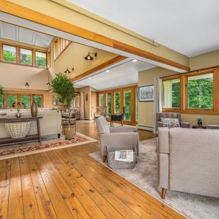 A spacious living room with modern furniture, large windows, and wood flooring.