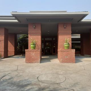 A brick building entrance with two green potted plants flanking the doorway.