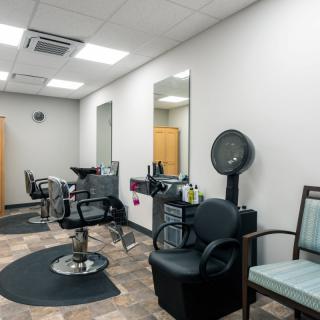 A modern and well-organized hair salon interior with chairs and mirrors.