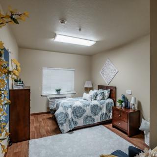 A cozy bedroom with a neatly made bed, wooden furniture, and soft lighting.