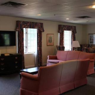 A cozy living room with sofas, a television, and large windows.